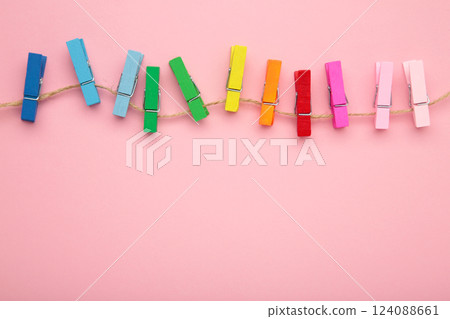 Colored wooden clothespins on a rope on pink background. Design elements. Macro. Colored wooden clothespins on a rope on pink background. Design elements. Macro. 124088661