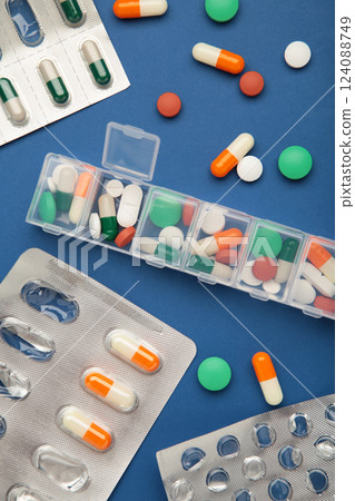 Daily pill box with medications and nutritional supplements on blue background. Space for text 124088749