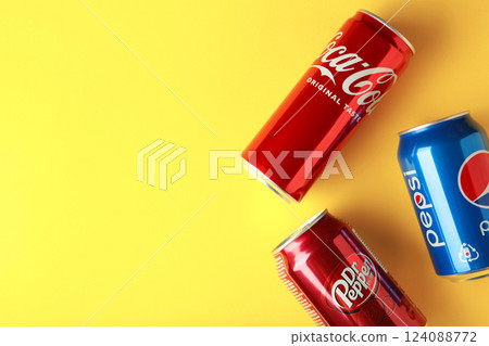 Mykolaiv, Ukraine - May 2, 2023: Cans of Coca cola, Pepsi, Dr.Pepper on yellow background. American multinational beverage company. Space for text 124088772
