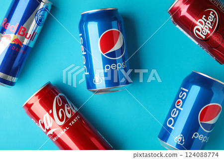 Mykolaiv, Ukraine - May 2, 2023: Cans of Coca cola, Pepsi, Dr.Pepper and Red Bull on blue background. American multinational beverage company 124088774