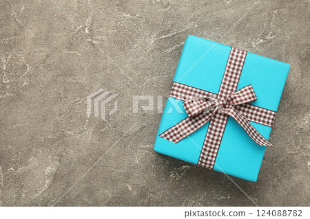 Blue gift box with brown ribbon on grey background. Space for text 124088782