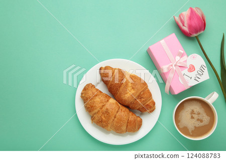 Happy mother's day, beautiful breakfast on mint background, lunch with cup of coffee, fresh croissants, tulip and gift. Spring holiday, family relations. 124088783