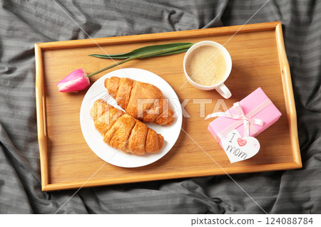Happy mother's day, beautiful breakfast on tray, lunch with cup of coffee, fresh croissants, tulip and gift. Spring holiday, family relations. 124088784