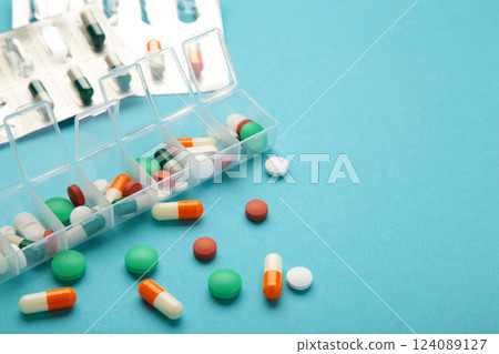 Daily pill box with medications and nutritional supplements on blue background. Space for text 124089127