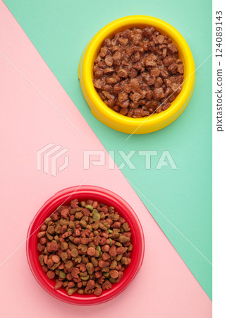 Wet and dry pet food in feeding bowls on colorful background. Vertical photo Wet and dry pet food in feeding bowls on colorful background. Vertical photo 124089143