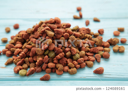 Dried cat food, shaped kitty kibble as an abstract background texture on blue wooden background. 124089161