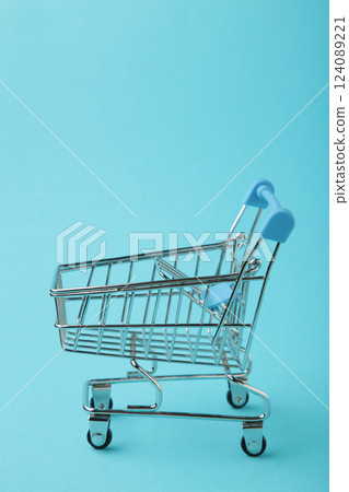 Mini shopping trolley on blue background. Vertical photo Mini shopping trolley on blue background. Vertical photo 124089221