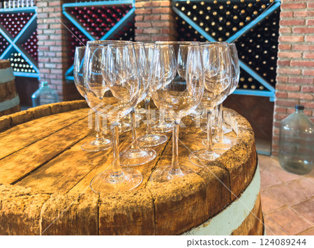 Many glasses of white wine on wooden barrel. Wine tasting event. Wine cellar with wine barrels. French wooden barrels. Wine shop wine bar winery or wine tasting concept Many glasses of white wine on wooden barrel. Wine tasting event. Wine cellar with wine barrels. French wooden barrels. Wine shop wine bar winery or wine tasting concept 124089244