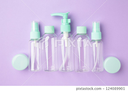 Empty travel cosmetic bottles on violet background. Minimalist bodycare beauty products for vacation or journey. Top view. Copyspace. 124089901