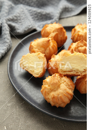 Homemade profiteroles with cream on plate on grey background. Fresh baked golden profiterole. Vertical photo Homemade profiteroles with cream on plate on grey background. Fresh baked golden profiterole. Vertical photo 124089925
