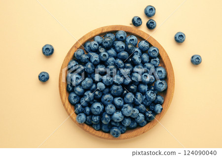 Fresh blueberry in wooden bowl on beige background. Top view. Concept of healthy and dieting eating 124090040