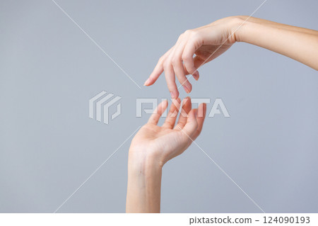 Delicate Interplay of Hands Displaying Connection and Touch Amidst a Soft Gray Background in a Captivating Artistic Composition 124090193