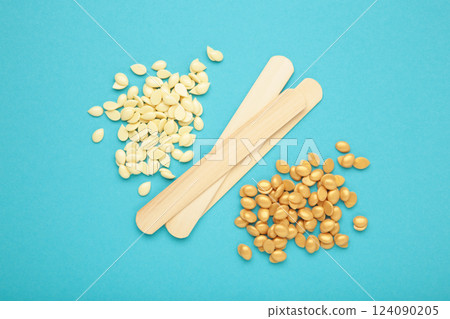 Sticks of wood for wax and spa with wax granules on blue background Sticks of wood for wax and spa with wax granules on blue background 124090205