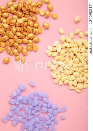 Different depilatory wax on pink background. Depilation wax granules. Epilation, depilation, unwanted hair removal. 124090217