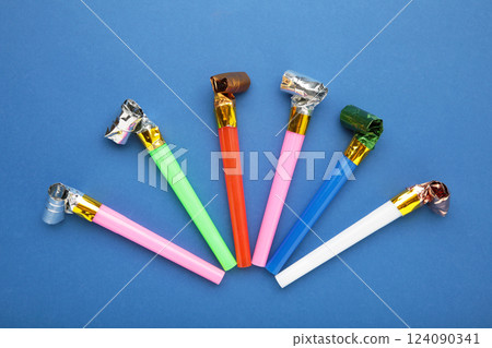 Party foil whistle or noise maker horn rolled on blue background. Party foil whistle or noise maker horn rolled on blue background. 124090341