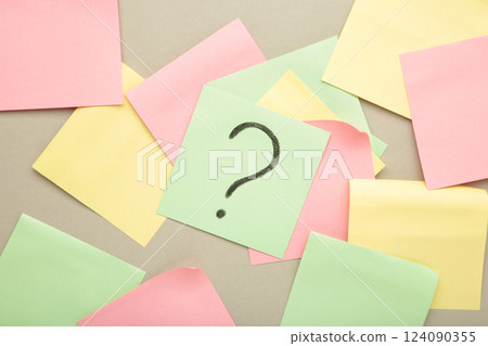 Question marks on colour stickers on grey background. Top view. Question marks on colour stickers on grey background. Top view. 124090355