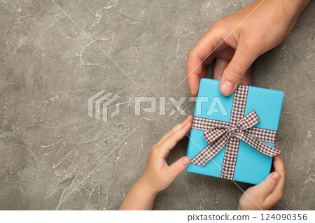 Father's day gift with daughter or son holding dad's hands giving present box to tell I love you dad, I am so thankful and happy fathers day. 124090356