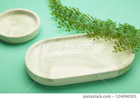 Mint plaster trays with green leaf on mint background. Stands for candles or jewelry Mint plaster trays with green leaf on mint background. Stands for candles or jewelry 124090381