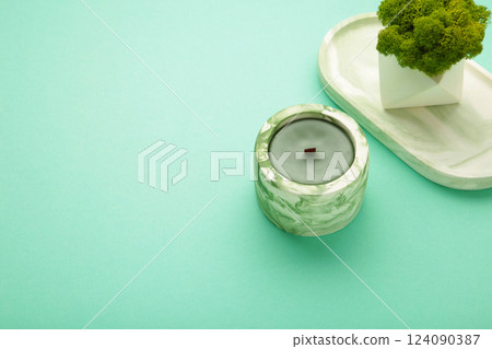 Interior candle in plaster candlestick and green plant on mint background. Space for text 124090387