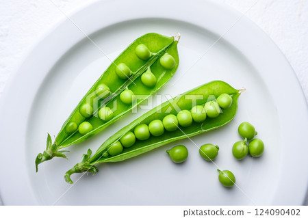 Top view on green sugar snap peas on white plate 124090402