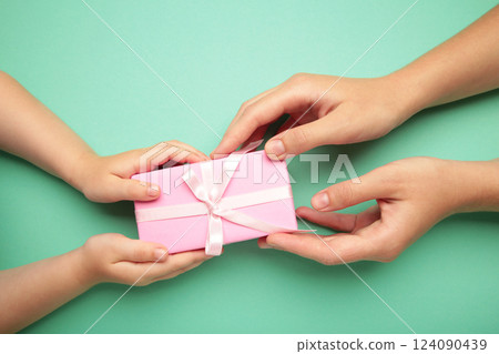 Mother's day gift with daughter holding mom's hands giving present box to tell I love you mom 124090439