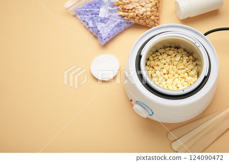 Electric wax warmer or wax heater with wax drops inside on beige background. Electric wax warmer or wax heater with wax drops inside on beige background. 124090472