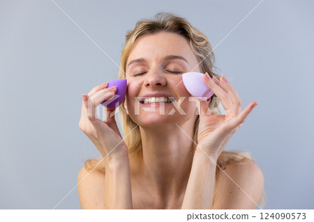 A Woman Enjoying Her Skincare Routine While Using Beauty Sponges for a Flawless Makeup Application and Healthy Skin in a Calm, Soft Atmosphere with Natural Lighting A Woman Enjoying Her Skincare Routine While Using Beauty Sponges for a Flawless Makeup Application and Healthy Skin in a Calm, Soft Atmosphere with Natural Lighting 124090573