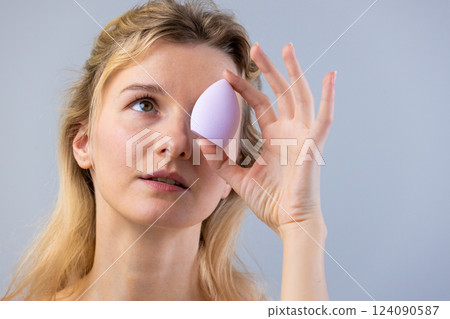 A Young Woman Experimenting with a Beauty Sponge: Capturing the Essence of Skincare and Makeup Application in a Creative and Engaging Way 124090587