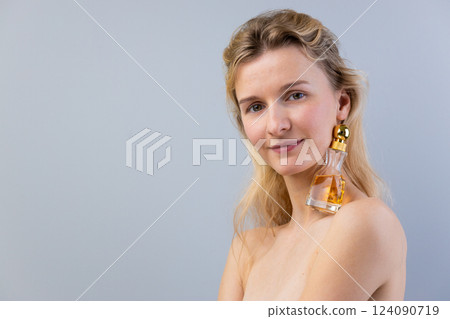Elegant and Artistic Portrait of a Woman Featuring Perfume Bottle as an Accessory on Her Bare Shoulder Against Soft Gray Background Elegant and Artistic Portrait of a Woman Featuring Perfume Bottle as an Accessory on Her Bare Shoulder Against Soft Gray Background 124090719