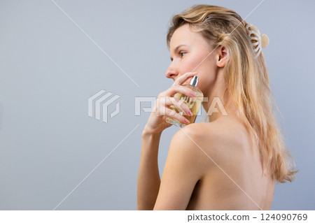 Elegant Woman Applying Perfume with Graceful Focus on Self-Care and Aesthetic Beauty in a Minimalistic Ambiance 124090769