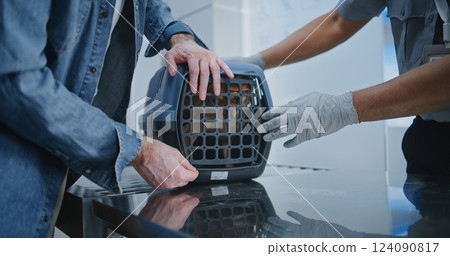 Dog Owner and TSA Officer Placing Dog in Carrying Case After Pet Screening Procedure in Airport 124090817