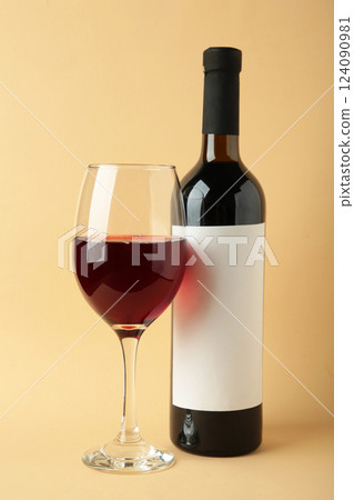 Wine bottle and wine glass on beige background. Vertical photo Wine bottle and wine glass on beige background. Vertical photo 124090981