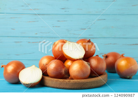 Fresh healthy onions and sliced onion on wooden board on blue background. Fresh healthy onions and sliced onion on wooden board on blue background. 124090987