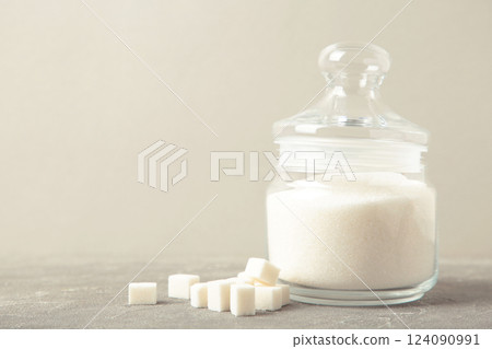 Jar with white sugar on grey background. Space for text 124090991