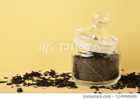 Large glass jar with tea leaves on beige background. Large glass jar with tea leaves on beige background. 124090999