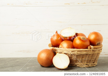 Ripe yellow onions in basket on grey background 124091005