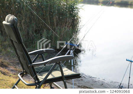Fisherman's chair and fishing rods in the background over the river at sunrise, foggy morning. Fishing concept. Fisherman's chair and fishing rods in the background over the river at sunrise, foggy morning. Fishing concept. 124091068