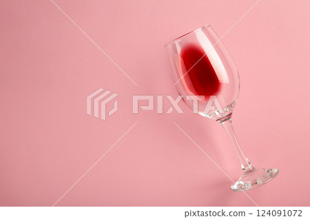 Glass with red wine lying on pink background, top view. Flat lay 124091072