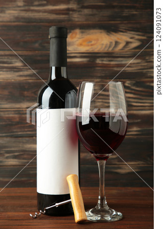Wine bottle and wine glass with grapes on brown wooden background. Vertical photo Wine bottle and wine glass with grapes on brown wooden background. Vertical photo 124091073