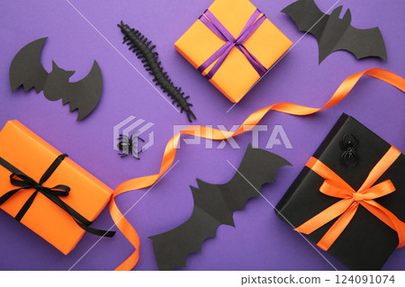 Happy Halloween holiday concept. Flat lay gift boxes, orange pumpkins, bats, spiders on violet background. Halloween greeting card template. Happy Halloween holiday concept. Flat lay gift boxes, orange pumpkins, bats, spiders on violet background. Halloween greeting card template. 124091074