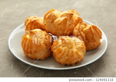 Homemade profiteroles with cream on plate on grey background. Fresh baked golden profiterole. Homemade profiteroles with cream on plate on grey background. Fresh baked golden profiterole. 124091118