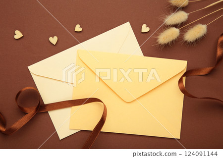 Beige envelope with ribbon on brown with a dried flowers. 124091144
