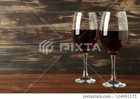 Dark studio shot of glasses of red wine on dark brown background. Space for text 124091173
