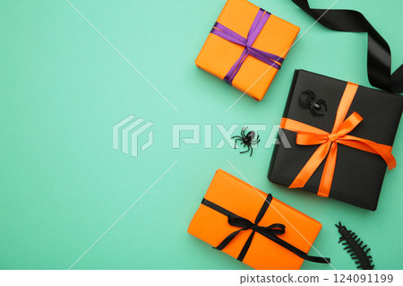 Happy Halloween holiday concept. Flat lay gift boxes with spiders on mint background. Halloween greeting card template. Happy Halloween holiday concept. Flat lay gift boxes with spiders on mint background. Halloween greeting card template. 124091199