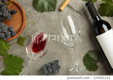Wine bottle and wine glass with grapes on grey concrete background. 124091252