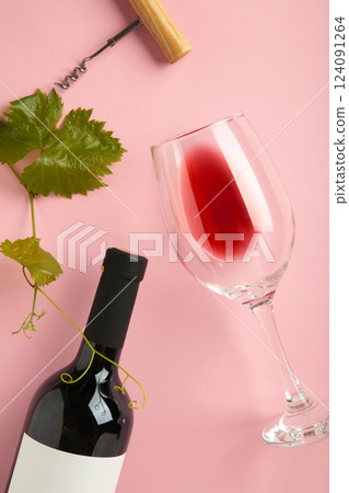 Wine bottle with wine glass and corkscrew lying on pink background. Vertical photo 124091264