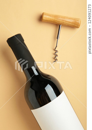 Bottle with red wine and corkscrew on beige background. Vertical photo Bottle with red wine and corkscrew on beige background. Vertical photo 124091273
