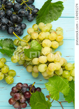 Assortment of different grapes on blue wooden background. Vertical photo Assortment of different grapes on blue wooden background. Vertical photo 124091274