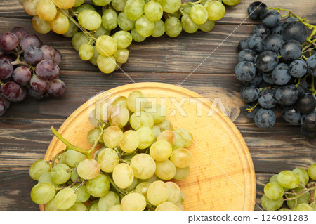 Assortment of different grapes on brown wooden background. 124091283