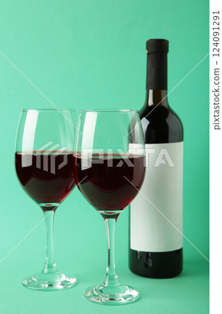 Wine bottle and wine glass on mint background. Vertical photo 124091291